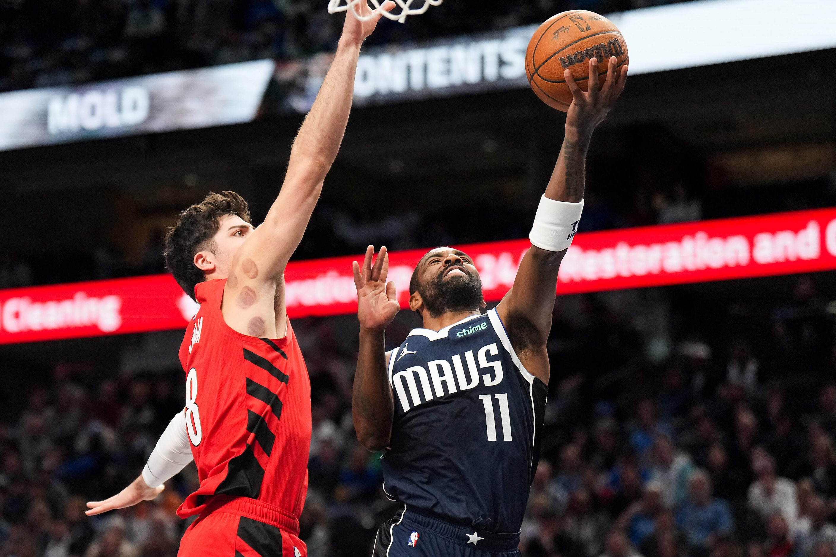 Dallas Mavericks guard Kyrie Irving (11) scores past Portland Trail Blazers forward Deni...