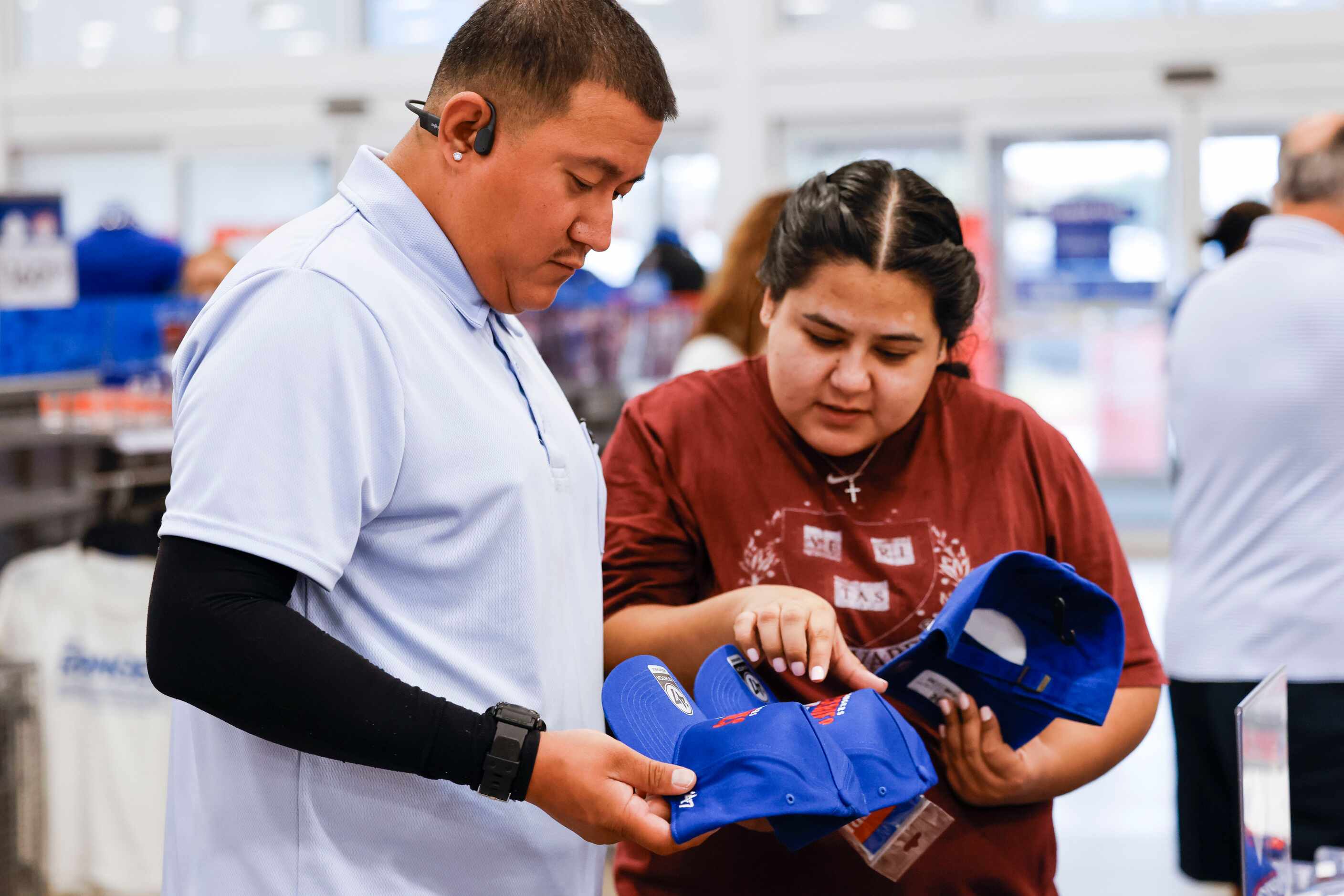 Andrew Carrillo and Giselle Herrera of Dallas look around for a Texas Rangers cap at Academy...