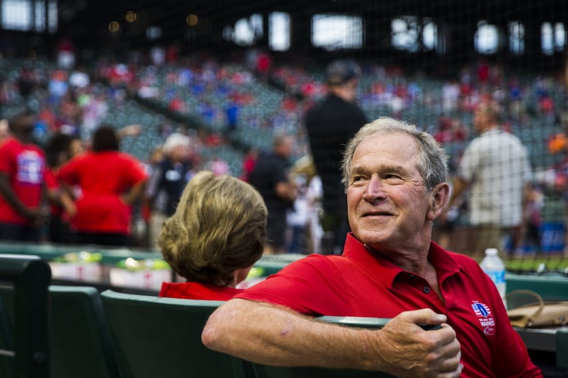 Former president of the United States George W. Bush looks over his shoulder to talk to a...