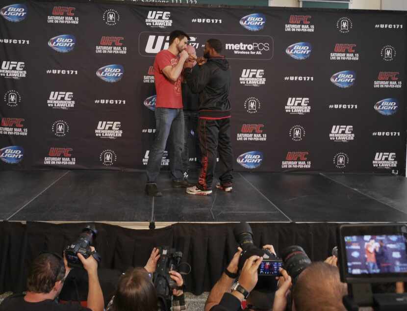 Carlos Condit, left, faces off with opponent Tyron Woodley, right, under the watchful eye of...