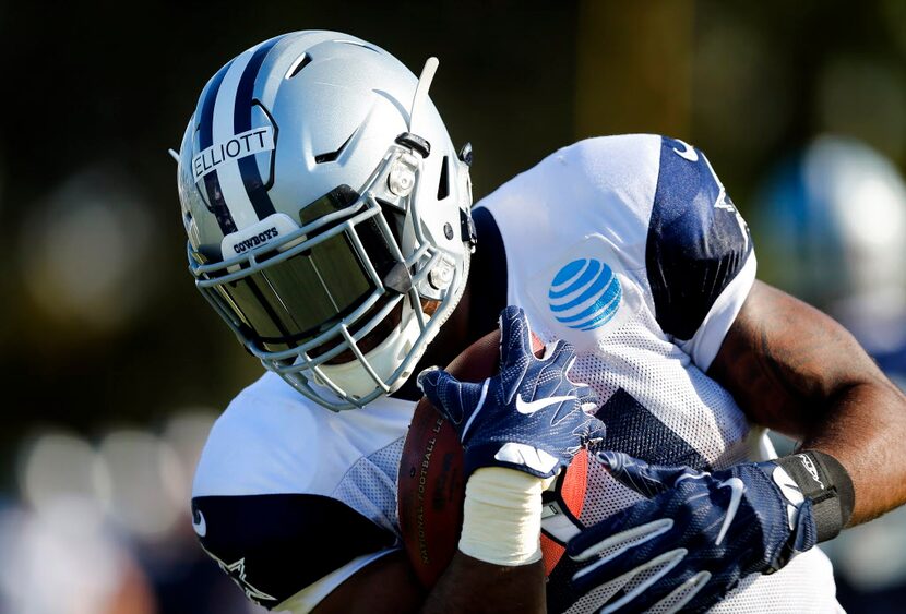 Dallas Cowboys running back Ezekiel Elliott (21) tucks the ball and runs during afternoon...