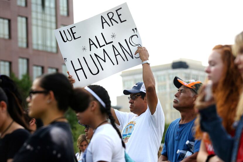 Pablo Rodriguez holds up a sign reading "We Are All Humans" during a vigil to remember the...