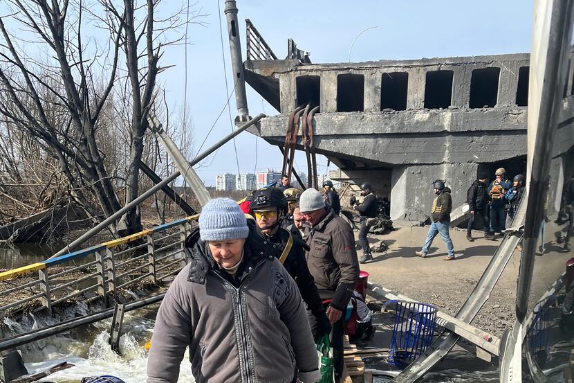 Fleeing Ukrainians navigate what's left of the Irpin Bridge near Kyiv on foot. The bridge...