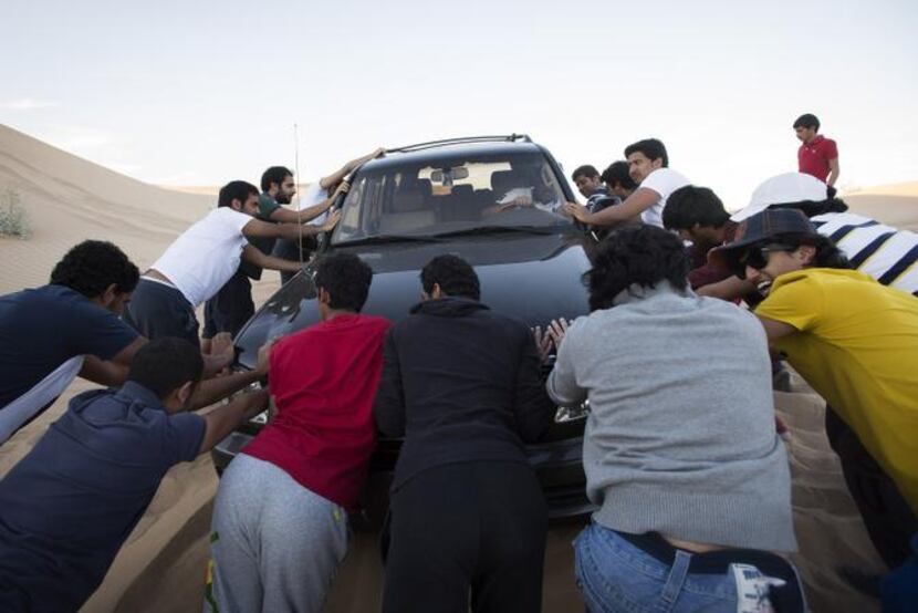 
San Diego State students push one of their vehicles after it got stuck in the sand in...