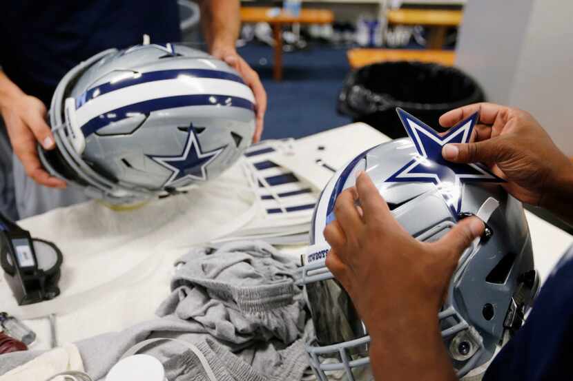 Frank Haight, left and Sterling Price, right, work on applying decals to helmets after...