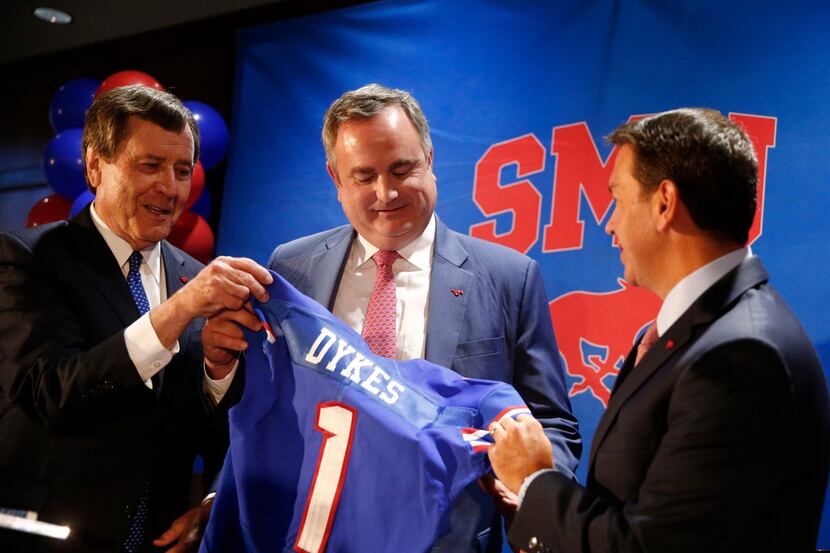 SMU president Gerald Turner (left) and athletic director Rick Hart (right) hand new SMU...