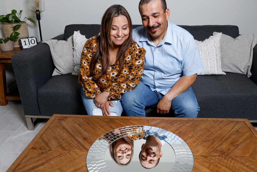 Thelma Ocampo (left) and Joel Ocampo look into their reflection in the living room of their...