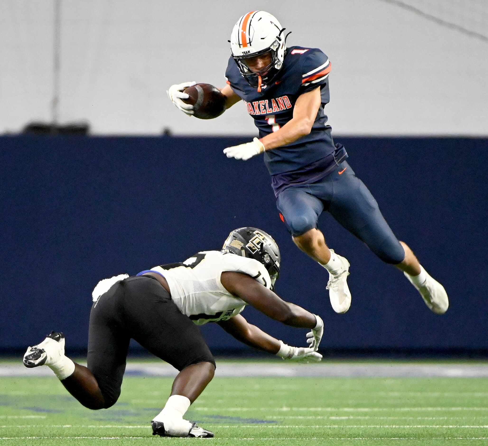 Frisco Wakeland's Davion Woolen (1) leaps over a tackle attempt by The Colony's Devin...