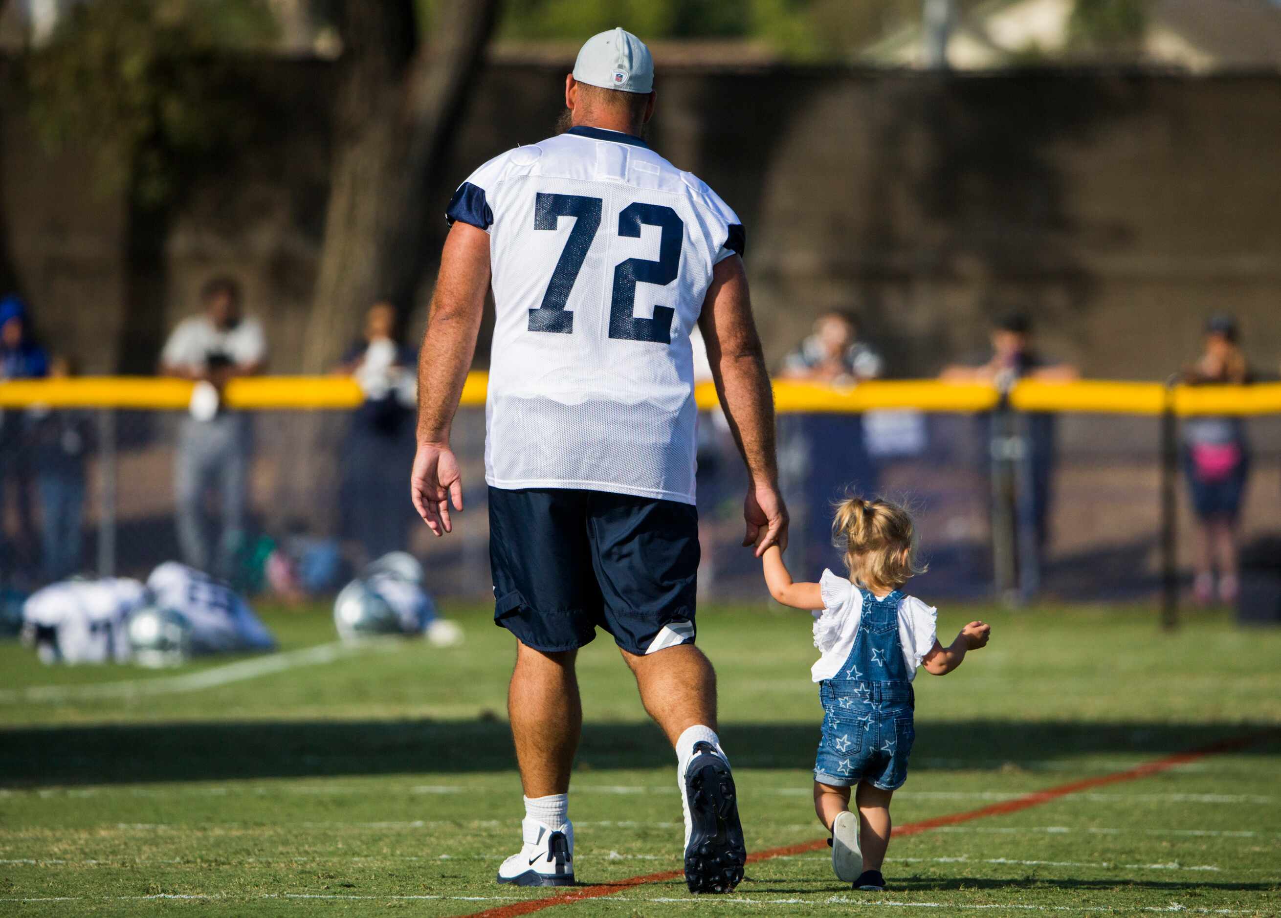 Dallas Cowboys center Travis Frederick walks with his daughter after an afternoon practice...