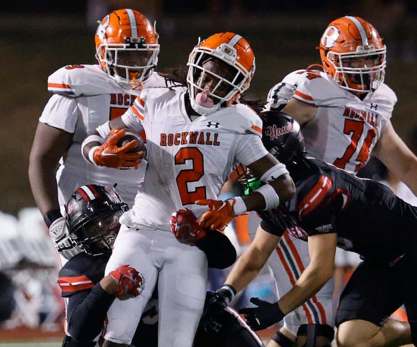 Rockwall's Ashten Emory (center) carries the ball as Rockwall-Heath defense players try to...