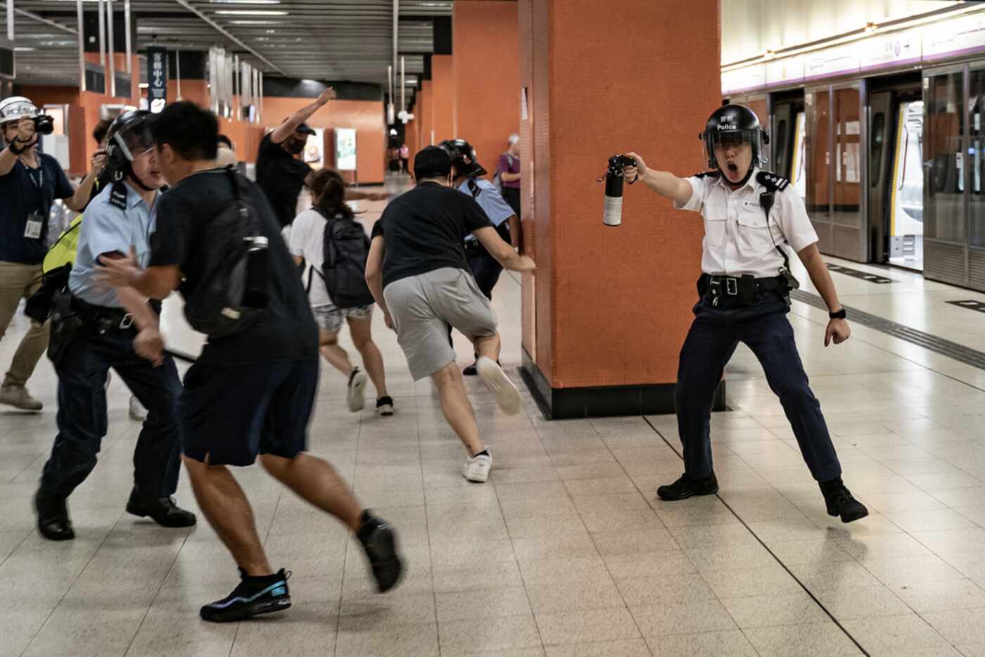 A police officer holds up pepper spray as he attempts to disperse protesters out of the...