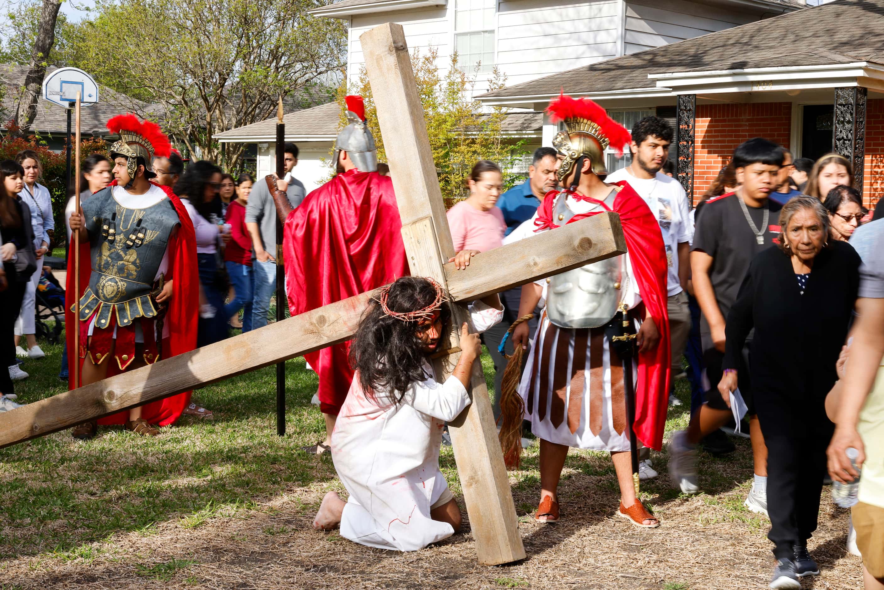 Parishioners walk around Bernie Gonzalez as he reenacts the sufferings of Jesus Christ...