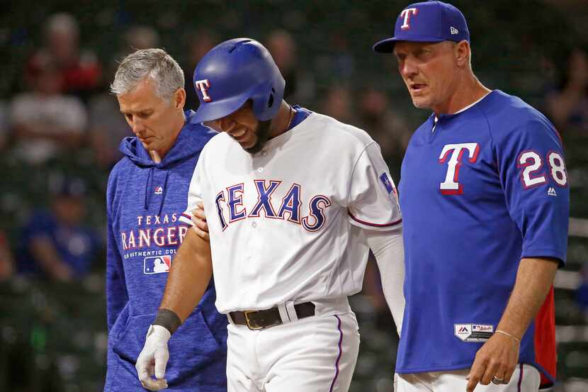 Texas Rangers shortstop Elvis Andrus, center, walks off the field with team athletic...