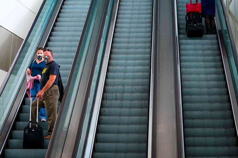 Passengers wearing face masks due to the new coronavirus ride an escalator at at  Dallas...