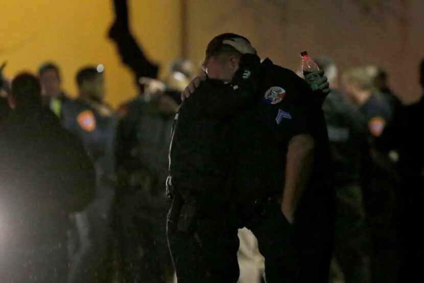 Police officers console each other outside the emergency room at Medical City Denton. (Jae...