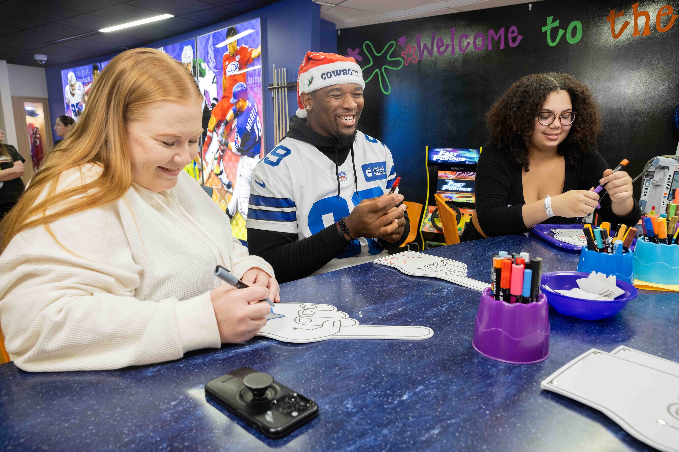 Dallas Cowboys defensive end Chauncey Golston (99) draws on foam fingers with Lanae...