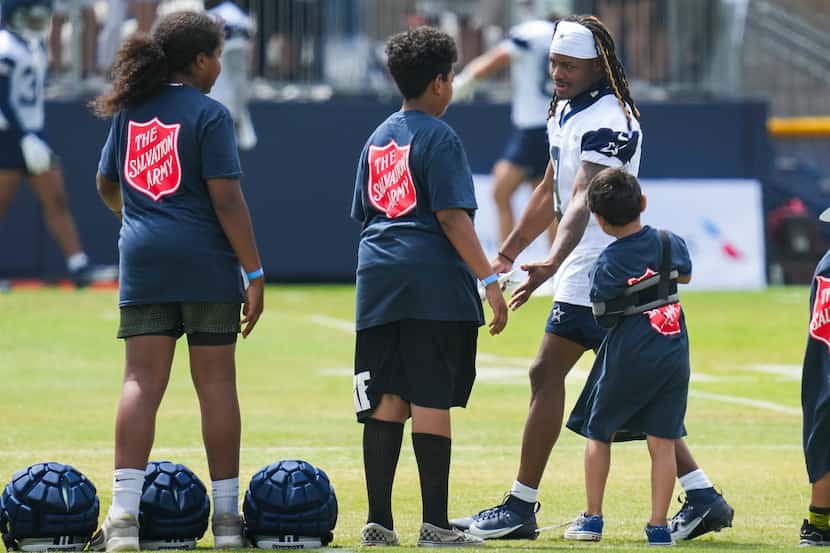 Dallas Cowboys wide receiver KaVontae Turpin slaps hands with youth football players serving...
