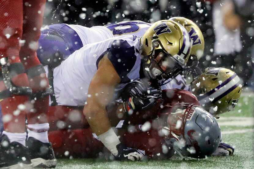 Washington State's Travell Harris is tackled by Washington safety Taylor Rapp as snow flies...