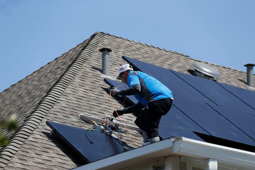 Roland Montoya, lead solar installer with Kosmos Solar, installs solar panels on a home in...