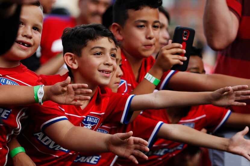 Fans reach toward FC Dallas players as they enter the field for an MLS soccer game against...