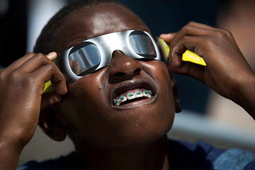 FILE - Blake Davis, 10, of Coral Springs, Fla., looks through solar glasses as he watches...