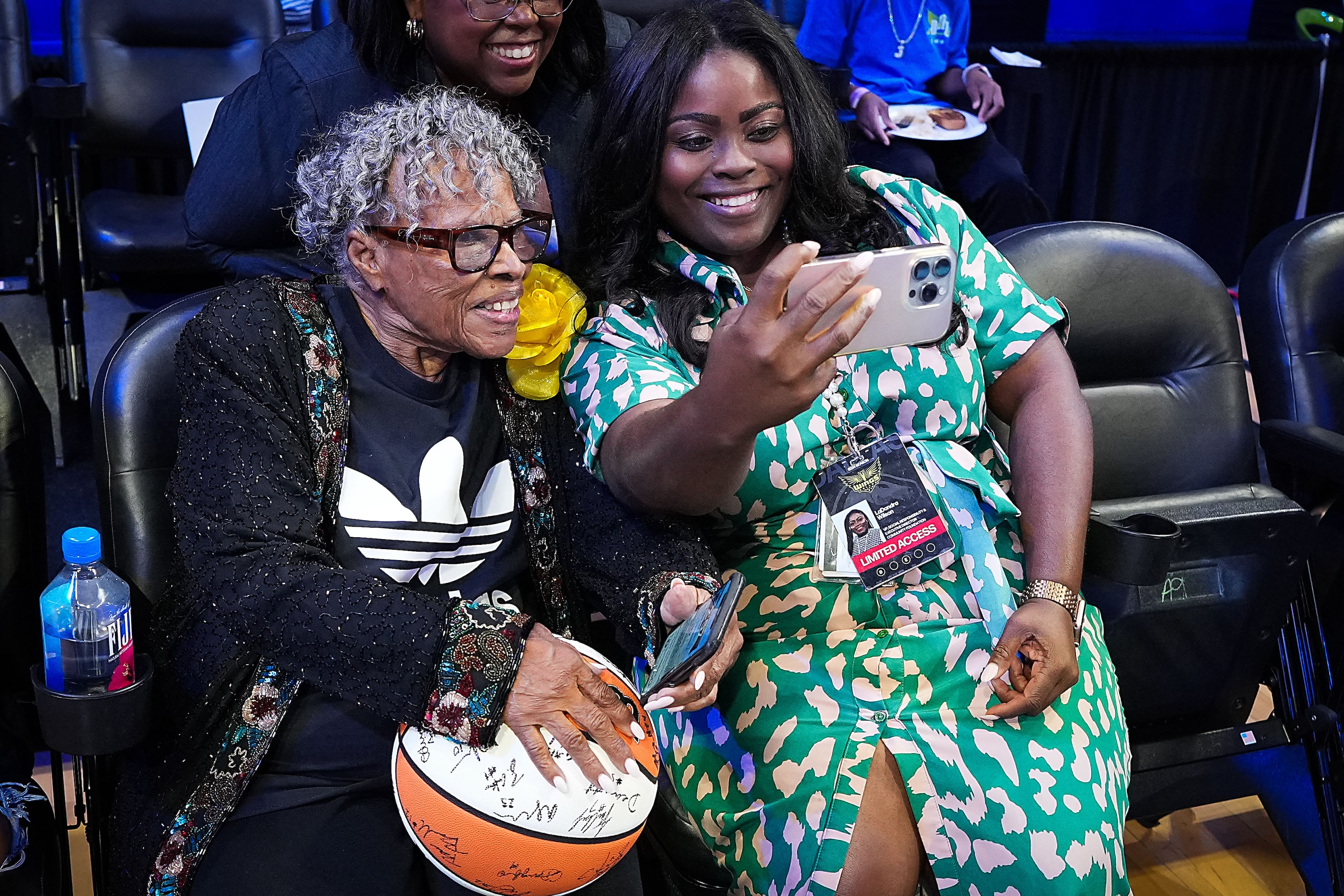 Opal Lee poses for photos while sitting courtside before a WNBA basketball game between the...