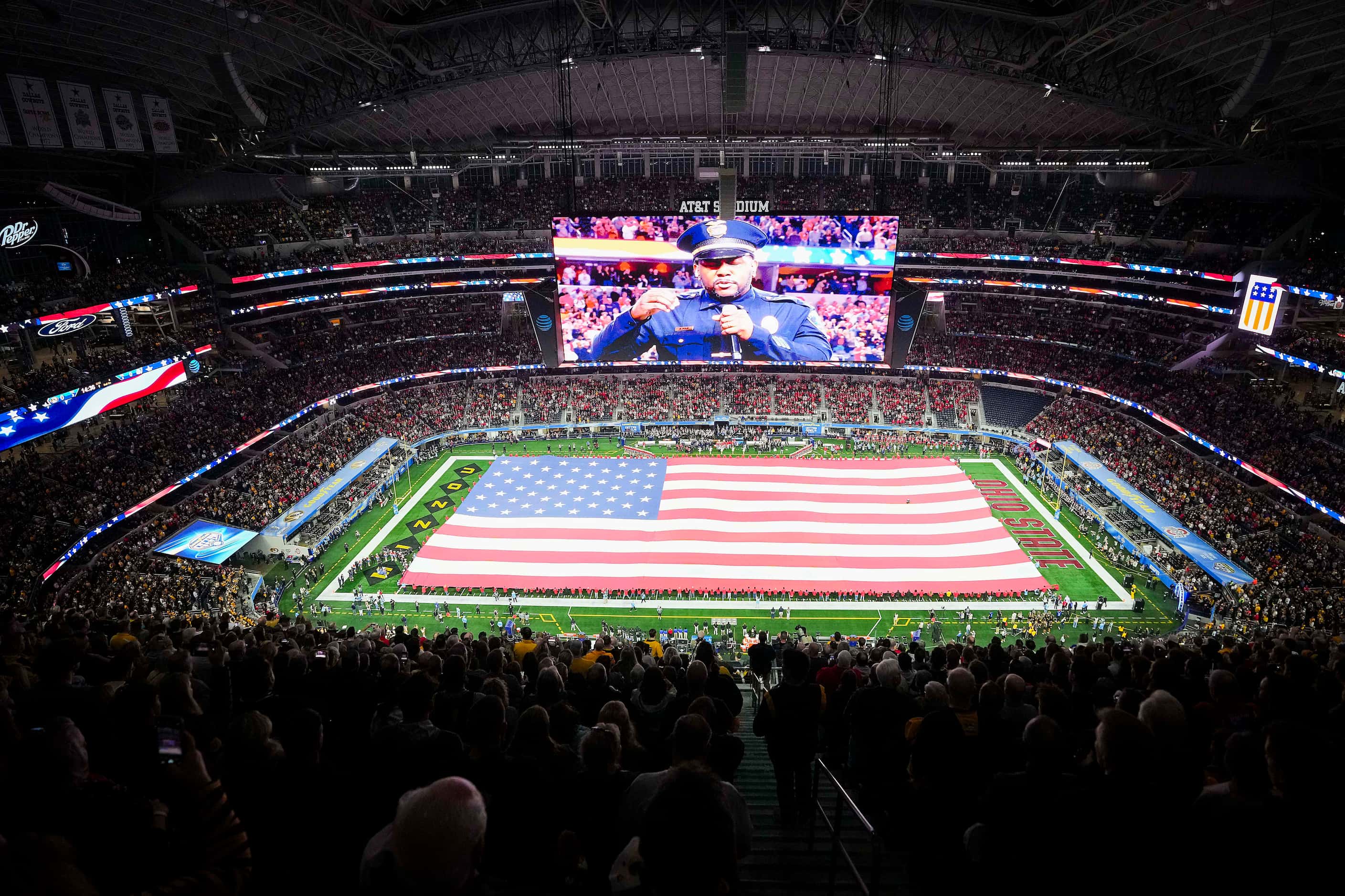 The American flag covers the field as Arlington Police Lt. Ray Polk sings the national...