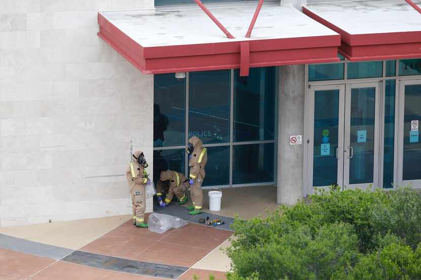 Dallas firefighters in hazmat suits collect a suspicious package left at the north entrance...