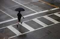 A man crosses a street in the rain, Thursday, May 16, 2024, in Dallas. 