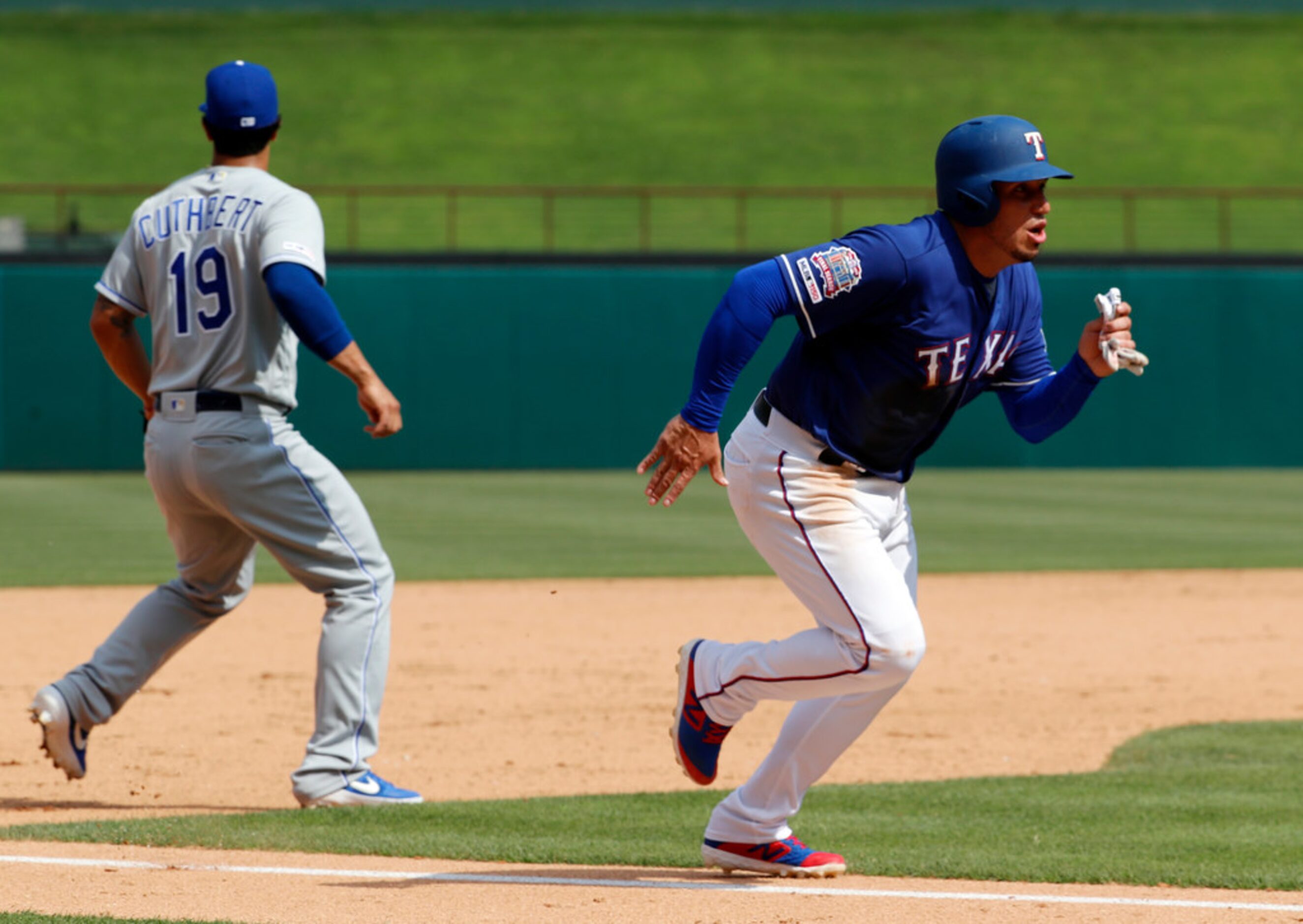 Kansas City Royals third baseman Cheslor Cuthbert, left, looks to the outfield as Texas...