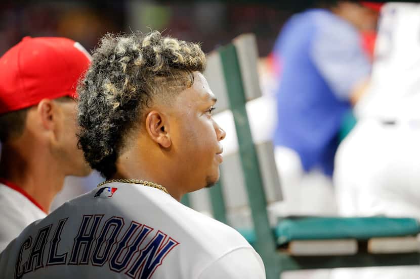 Texas Rangers' Willie Calhoun stands in the dugout in the fifth inning of a baseball game...