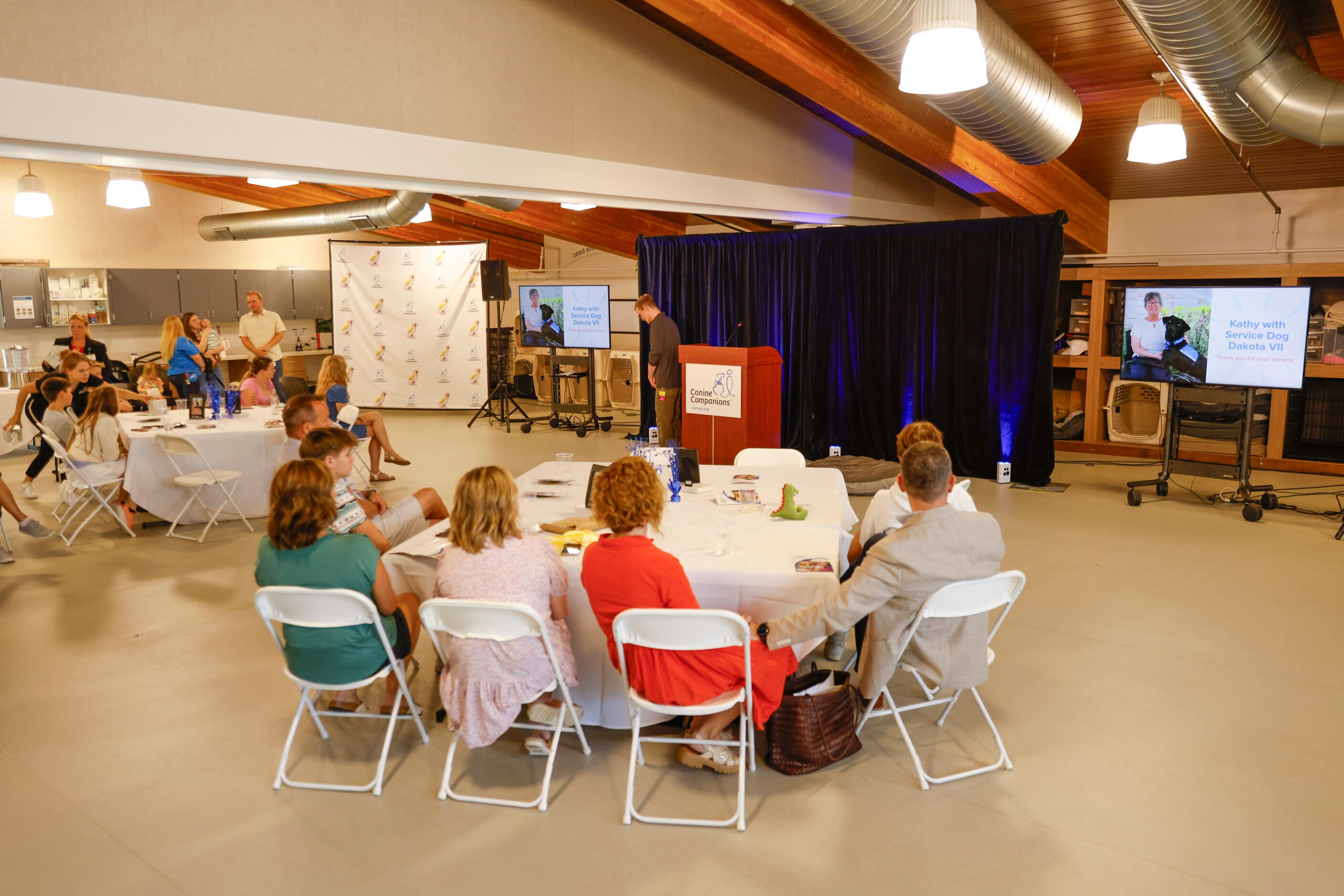 Attendees watch a video presentation during a service dog graduation ceremony on Friday,...