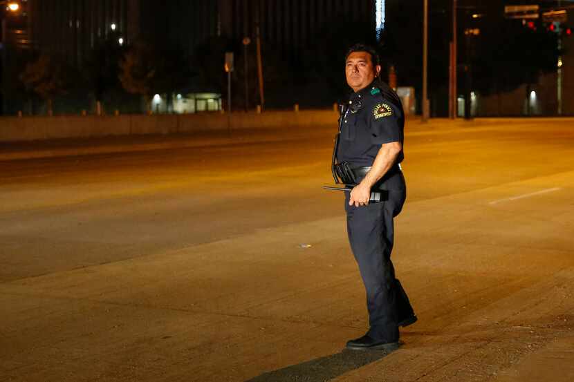 Dallas Police Deputy Chief Israel Herrera searches for bullet casings and other evidence at...