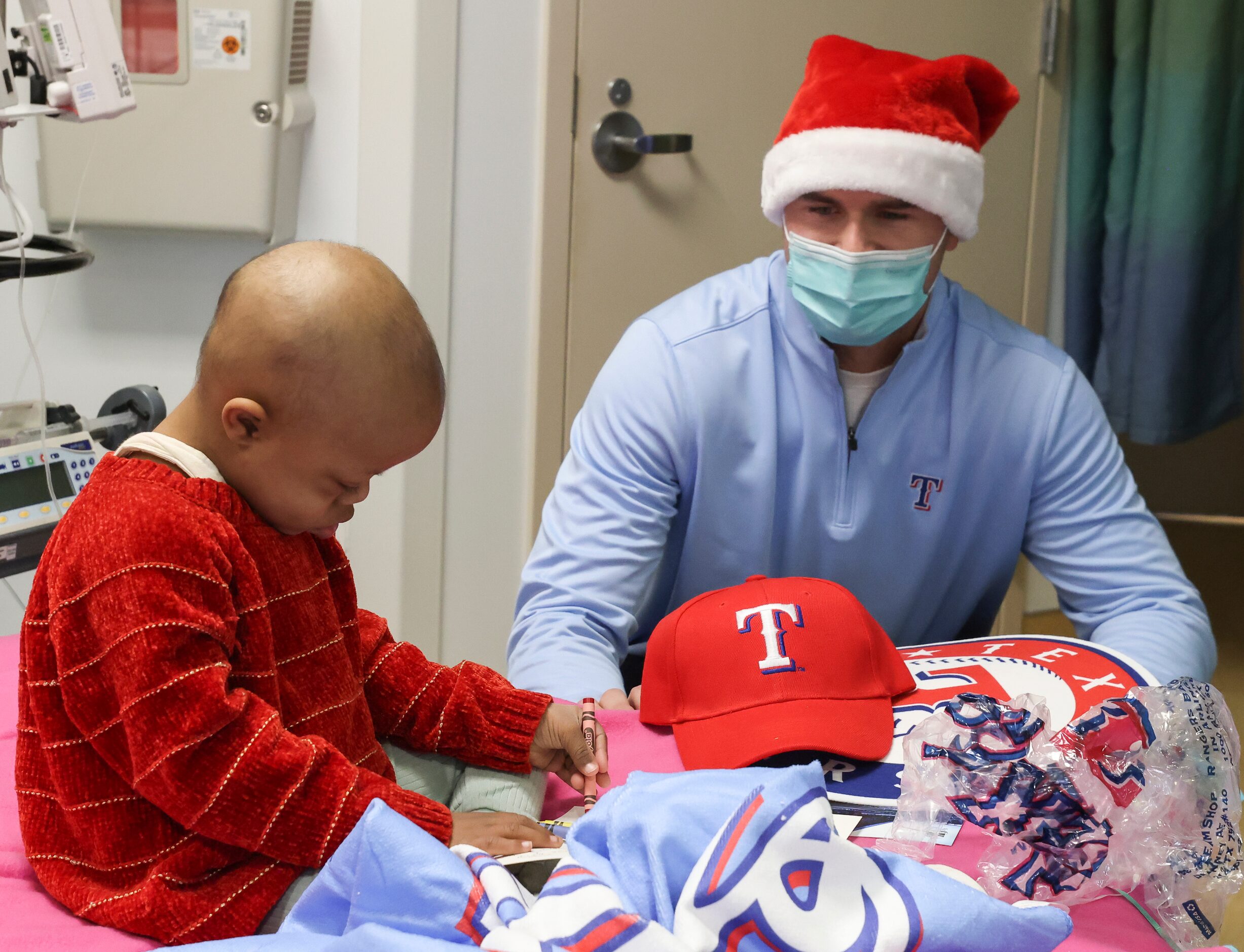 Texas Rangers pitcher John King watches as Isabella Pickens, 3, colors, at Medical City...