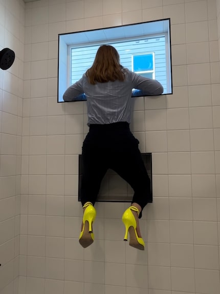 Woman looking out of shower window while wearing yellow high heels.