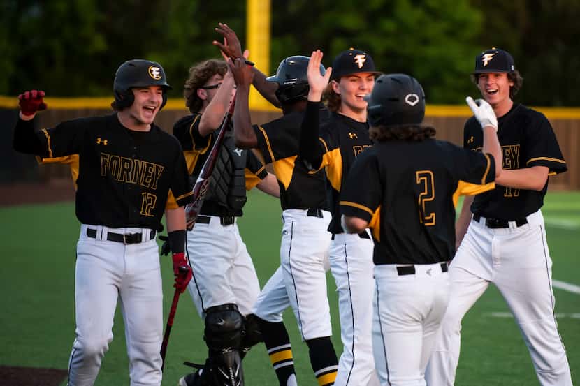 Forney players congratulate their teammates for scoring two runs during a baseball game...