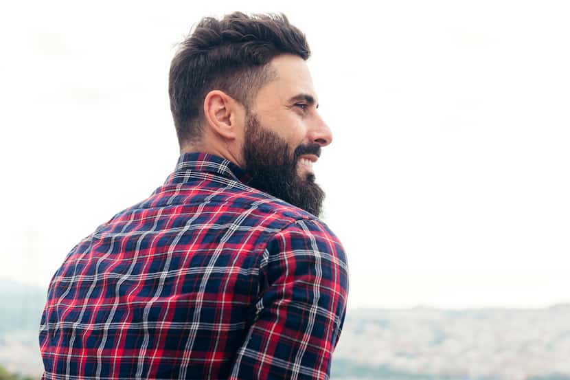 A bearded man in a plaid shirt smiles.