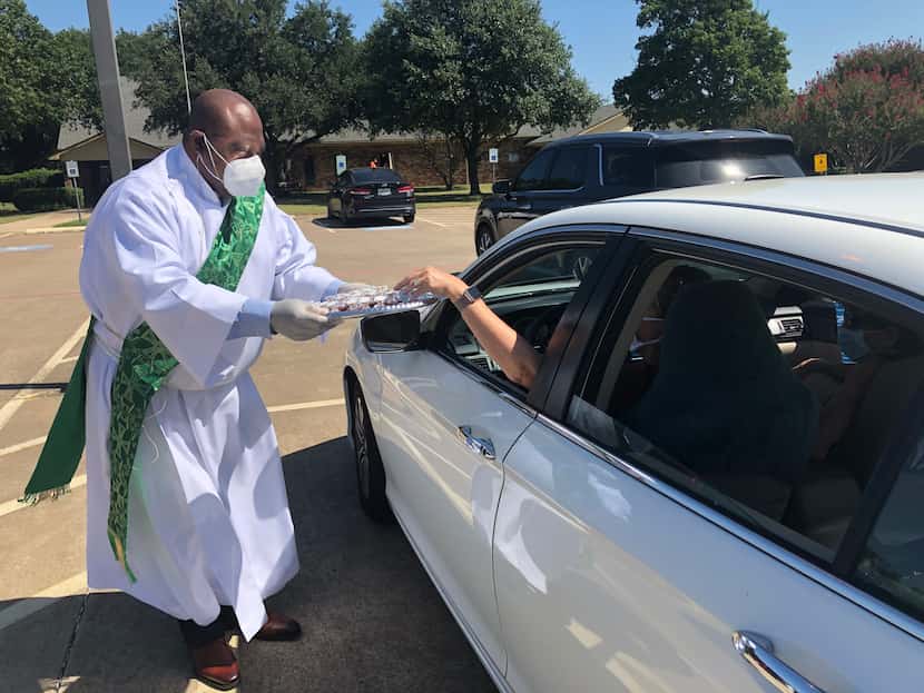 The Rev. Ayo Omoniyi goes from car to car in the St. Martin-in-the-Fields Church in...