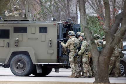 A law enforcement team stages behind an armored vehicle outside Congregation Beth Israel in...