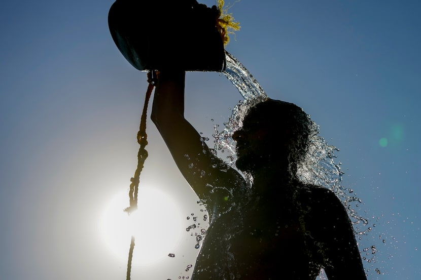 A man rinses with fresh water after playing beach volley ball on a sweltering hot day, at...