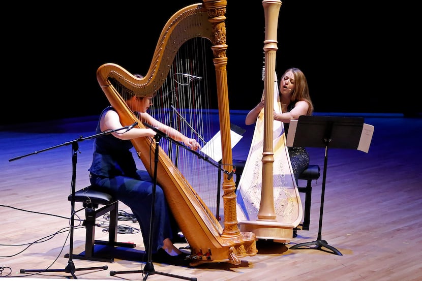 Harpists Emily Levin (left) and Michelle Gott sing while playing harp in a performance of...