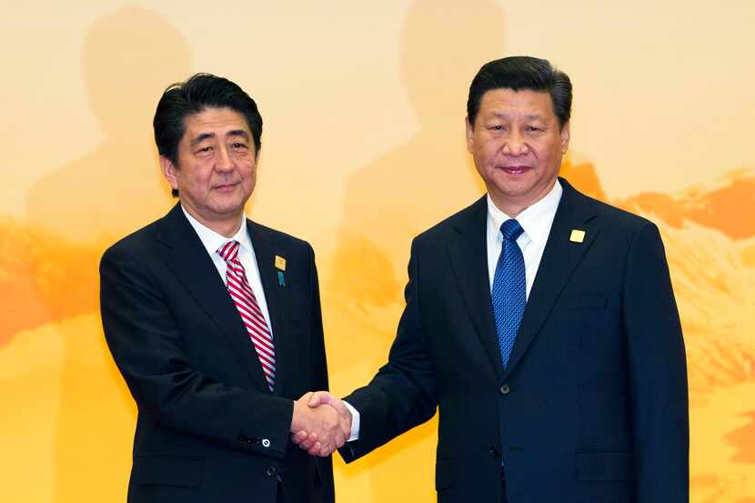 Japan's Prime Minister Shinzo Abe shakes hands with Chinese President Xi Jinping during a...