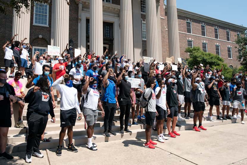 SMU athletes raise their fists as they chant outside of Dallas Hall during a march for the...