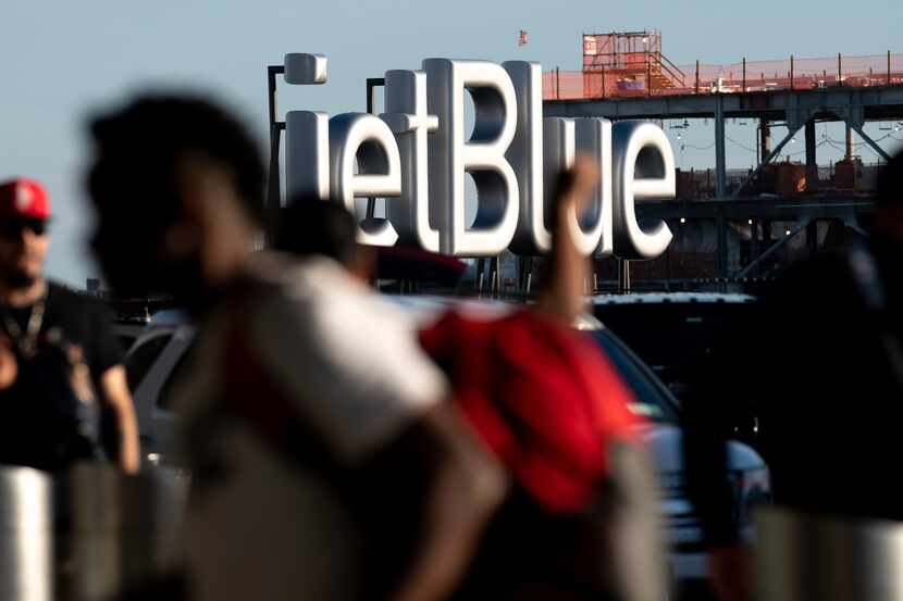 Viajeros pasan junto a un cartel de JetBlue antes del fin de semana feriado del 4 de julio...