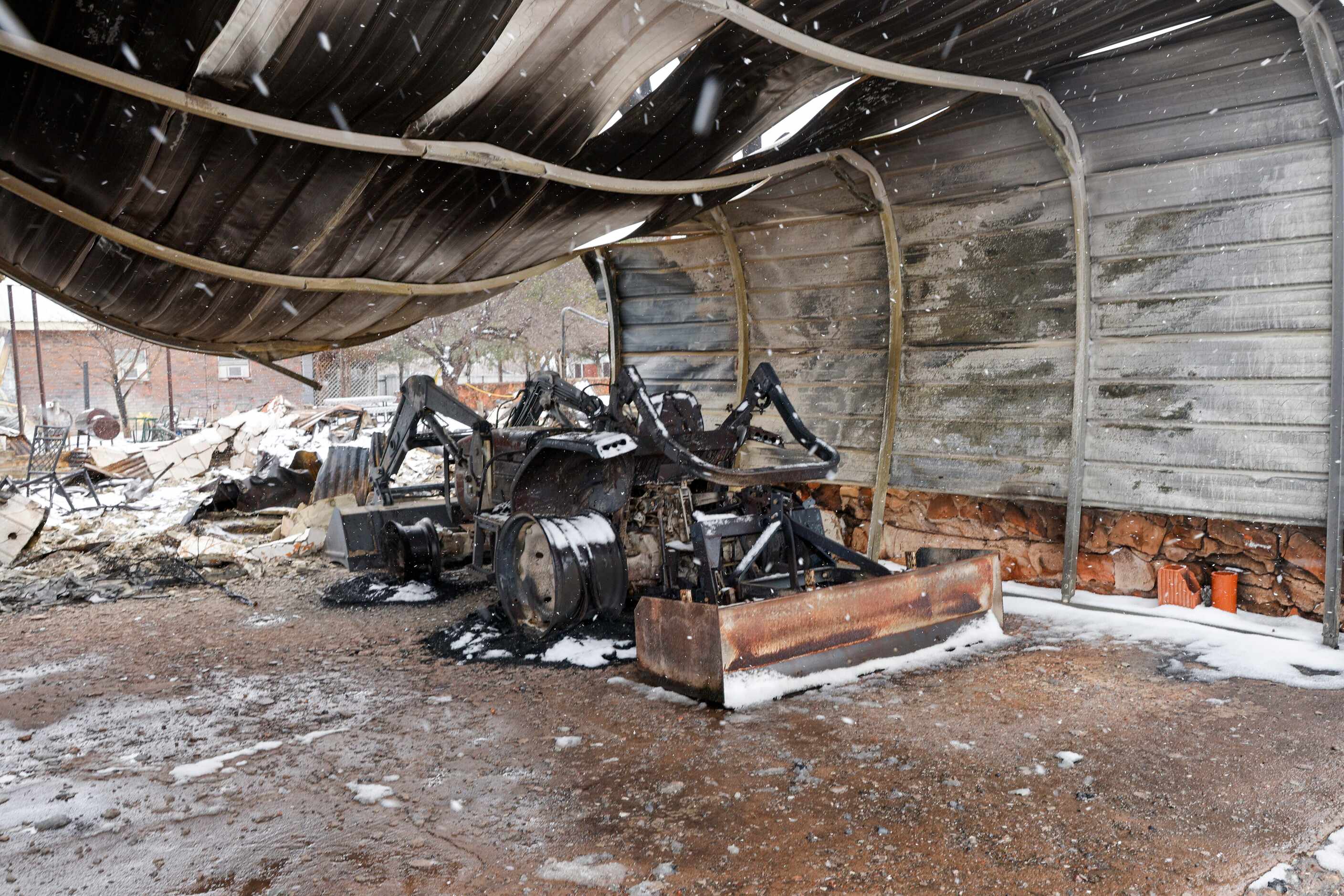 A charred tractor sits under a carport damaged by the Smokehouse Creek Fire, Thursday, Feb....