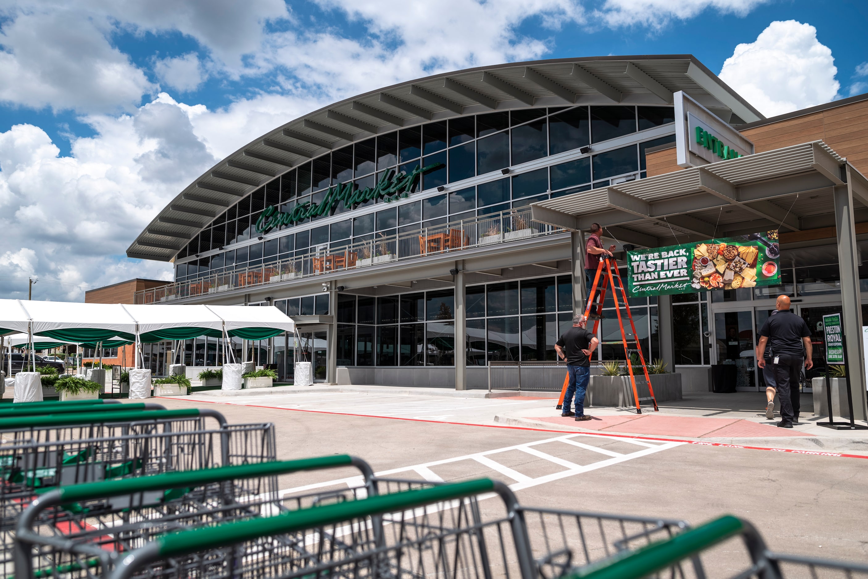 Employees hang signs as they prepare for the opening Wednesday of the rebuilt Central Market...