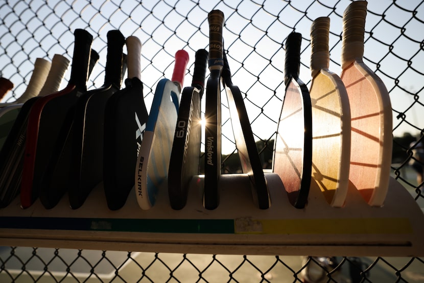 Players stack their paddles as they wait for courts to play pickleball.