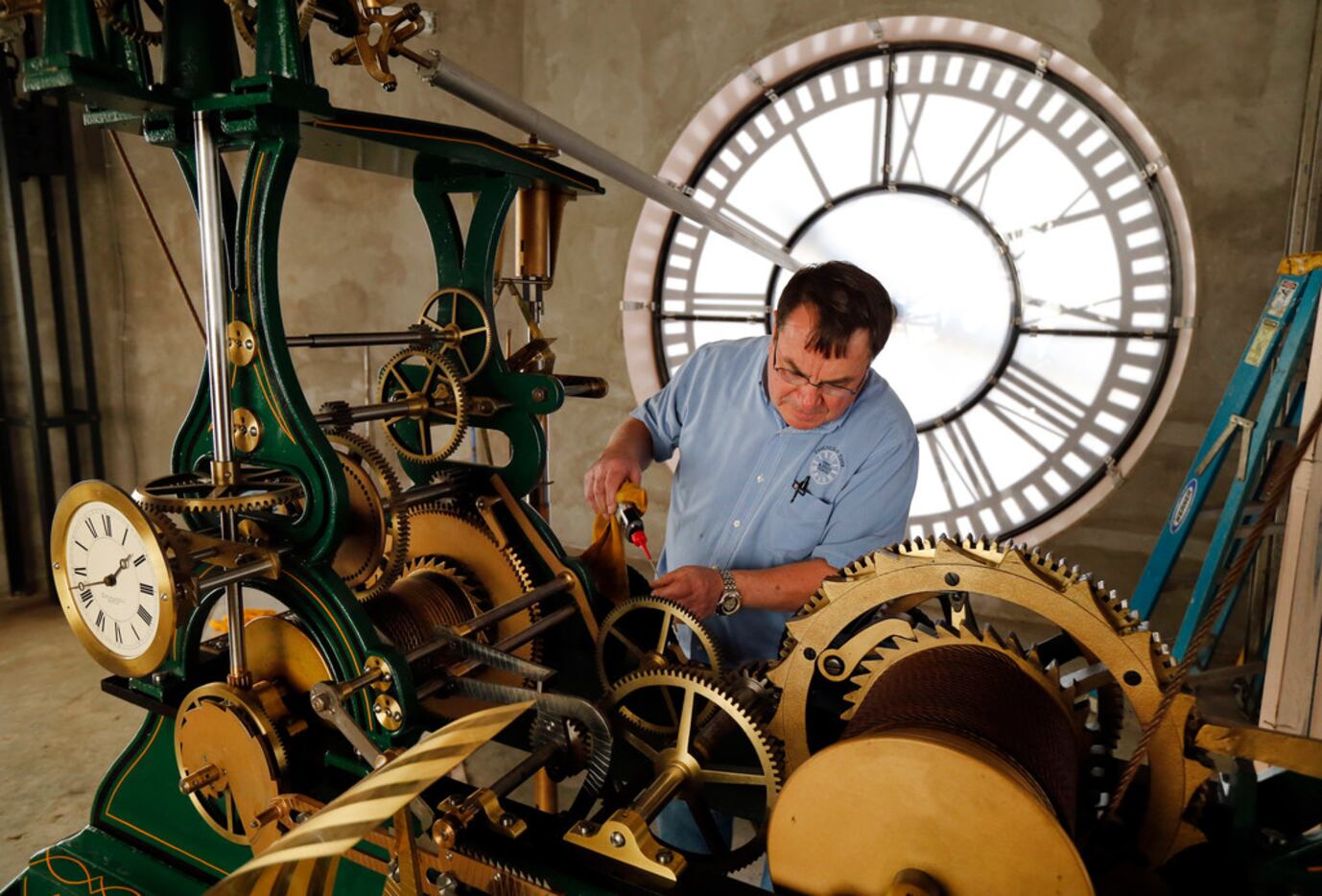 Historic clock restoration specialist Chuck Roeser of Lockport, New York lubricates the E....