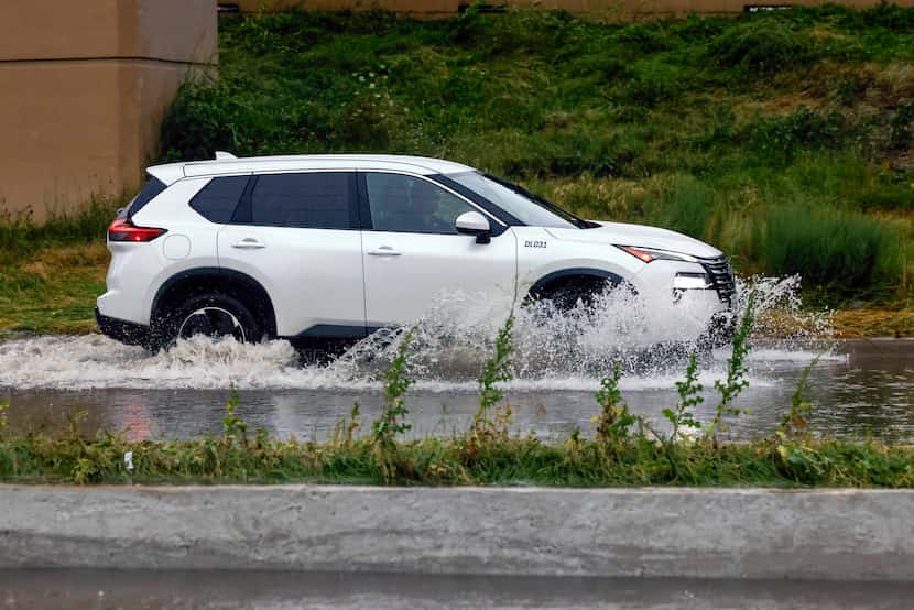 A motorist moved through a flooded service road along Interstate 35E near Royal Lane after a...