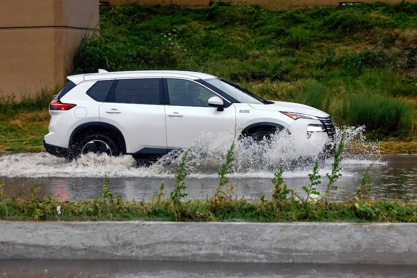 A motorist moved through a flooded service road along Interstate 35E near Royal Lane after a...